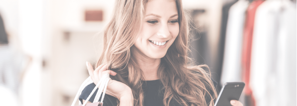 Woman shopping with bag over her shoulder while looking at her smartphone