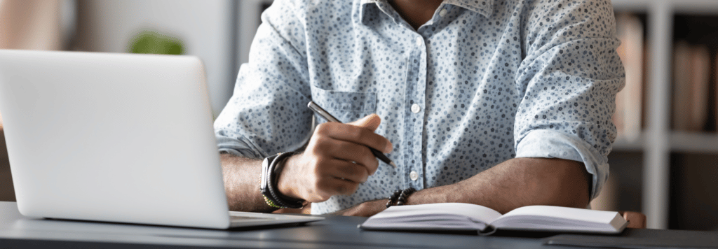 Person looking at laptop and taking notes