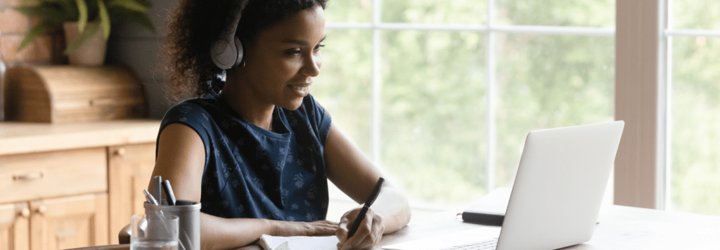 Woman looking at laptop and writing notes