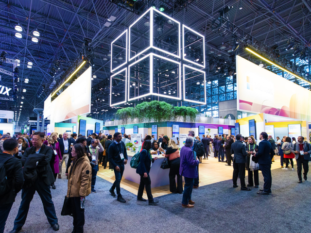 Crowded view of the NRF 2026 Retail’s Big Show expo floor at the Javits Center in New York City, showing attendees walking between large, brightly lit exhibitor booths focused on retail technology and clienteling solutions.
