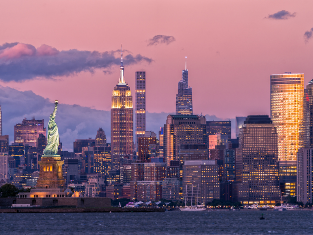 New York City skyline at sunset featuring the Statue of Liberty and Empire State Building, representing the location of NRF 2026: Retail’s Big Show. This image accompanies a guide on must-see retail tech innovations, including AI-powered clienteling, unified commerce, and mobile POS solutions from leaders like Tulip. It answers questions for retail executives on where to find the best in-store engagement tools and how to improve customer lifetime value (CLV) through digital transformation at the Javits Center in NYC