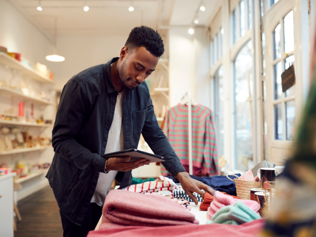 A retail store associate using a mobile clienteling app on a tablet to provide personalized service to a customer in-store.