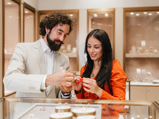A professional retail associate in a high-end jewelry store provides personalized assistance to a customer, demonstrating modern clienteling and expert-led product guidance.